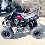 Four-wheeler parked on a sandy surface with trees in the background