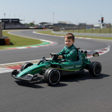 Child in a green toy Formula 1 car on a race track