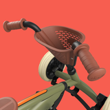 Close-up of a children's pedal-go-kart with brown handlebar grips and basket on a red background