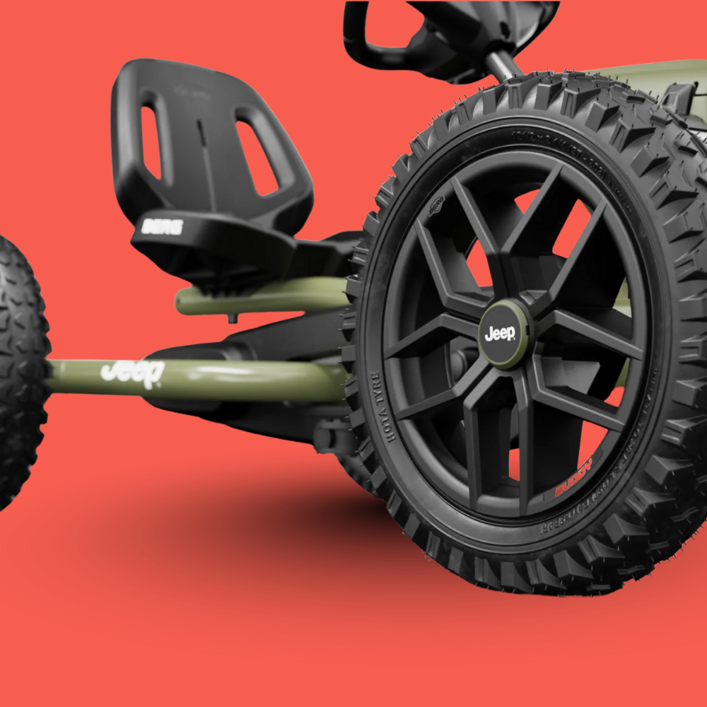 Close-up of a Jeep brand off-road vehicle with large black tires on a red background