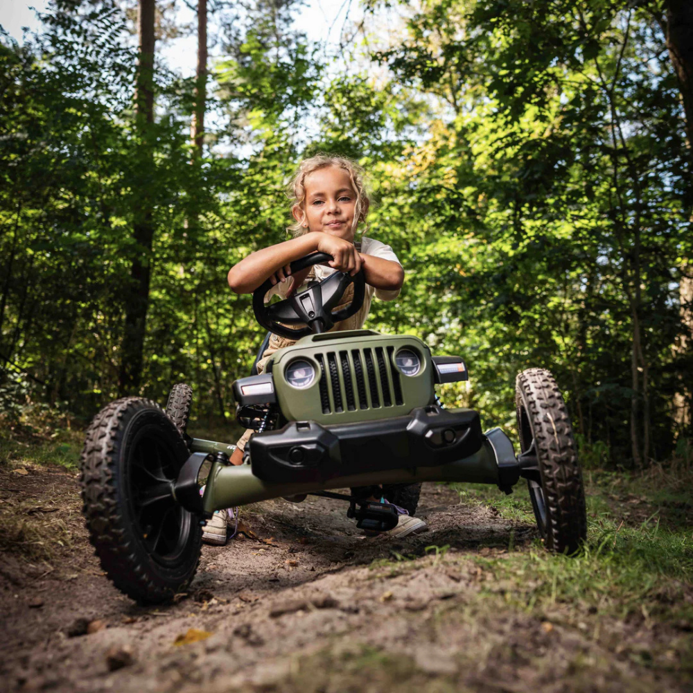 Child riding a toy jeep in a forest setting