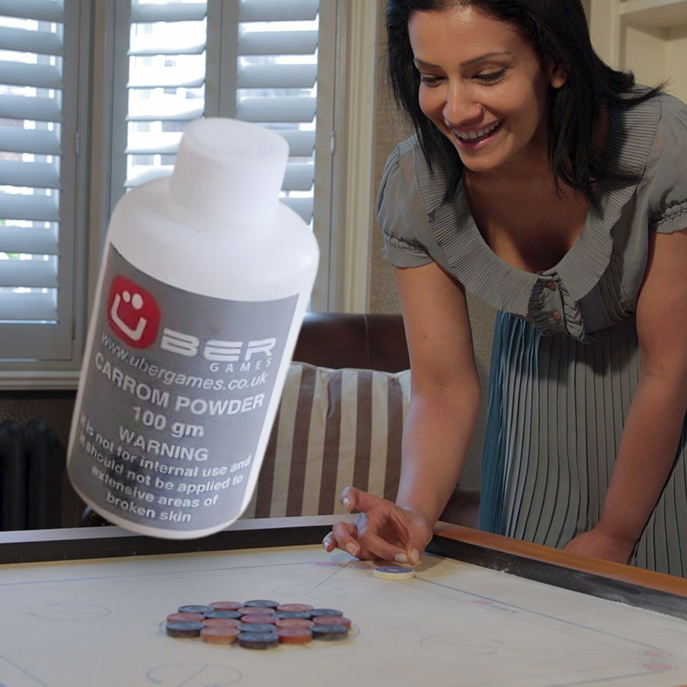 Woman preparing to take a shot on a carrom board, with a large Uber Games carrom powder 100g bottle in the foreground