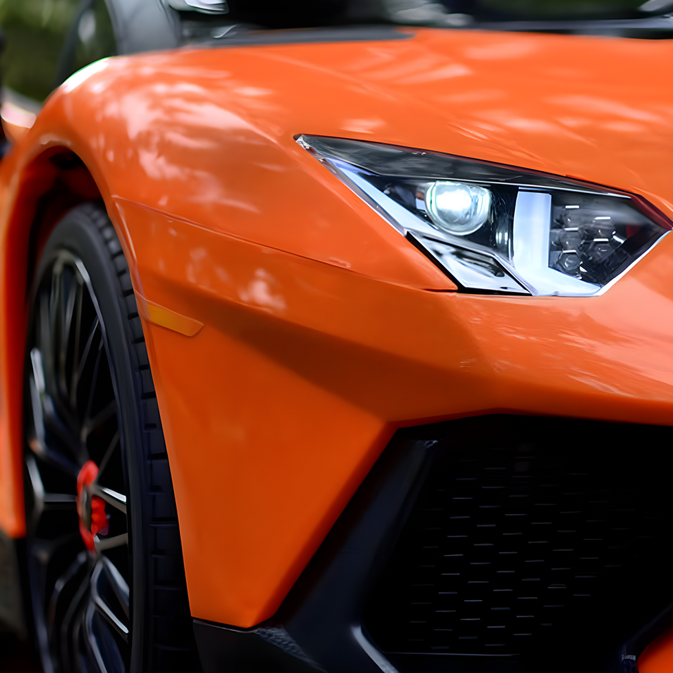 Close-up of the front of an orange sports car, showcasing its sleek headlights and aggressive design lines