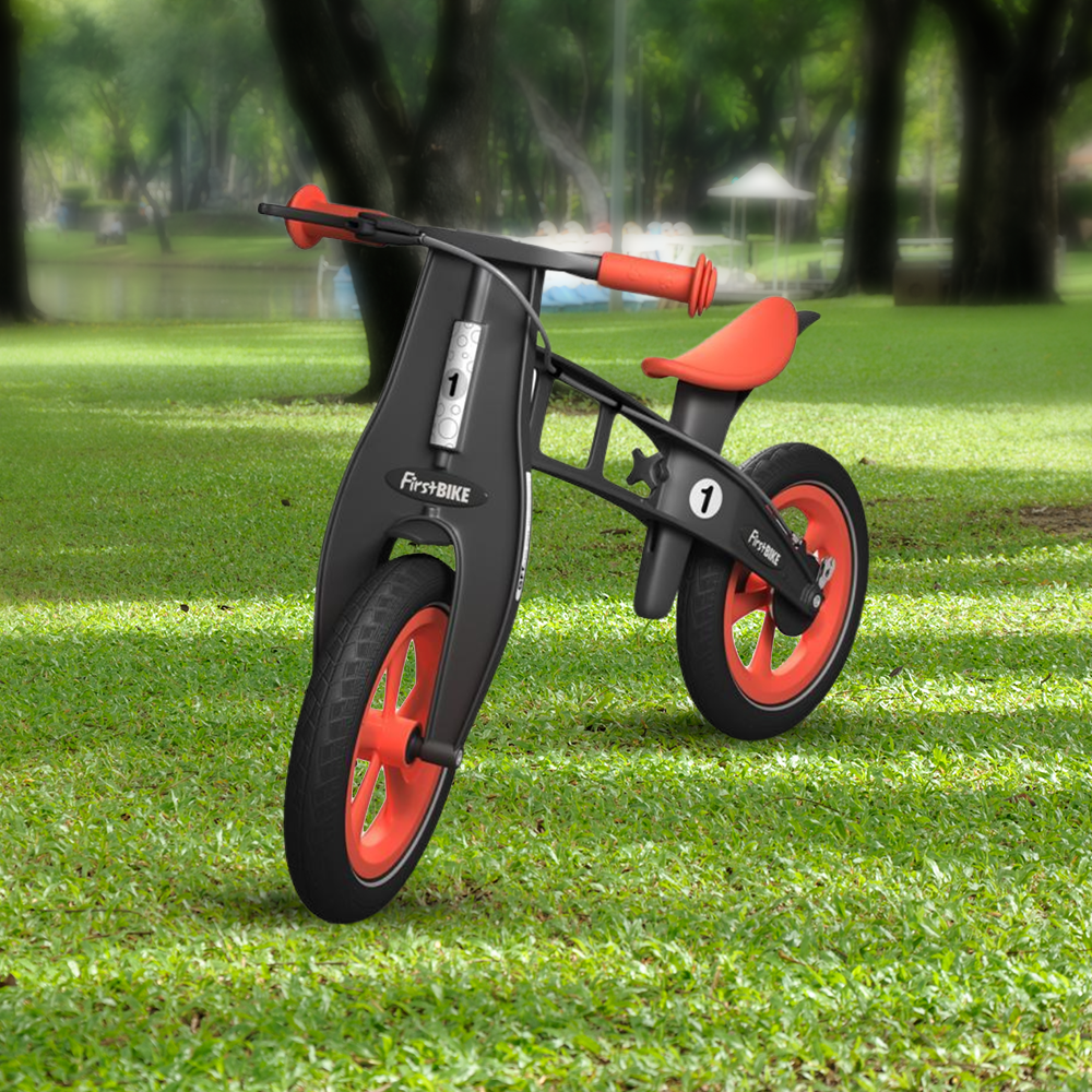 outdoor park with the FirstBIKE Limited Edition Balance Bike with Brake - Orange