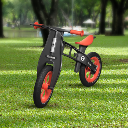 outdoor park with the FirstBIKE Limited Edition Balance Bike with Brake - Orange