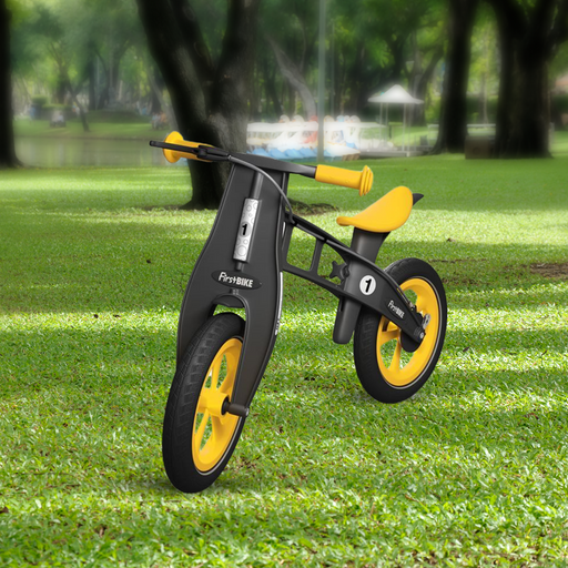 outdoor park with the FirstBIKE Limited Edition Balance Bike with Brake - Yellow
