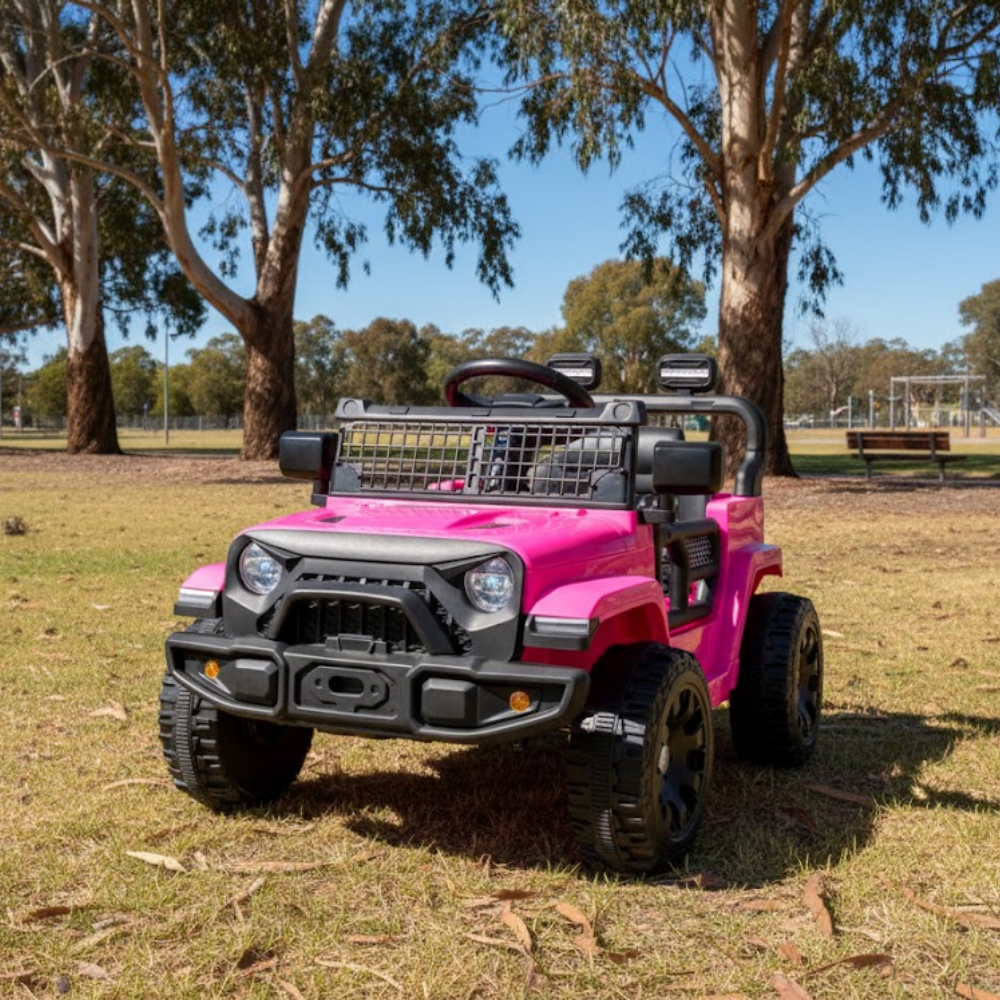 Pink toy jeep on grass with trees in the background