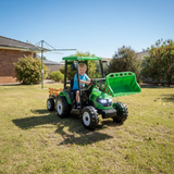 Child playing with a green toy tractor on grass