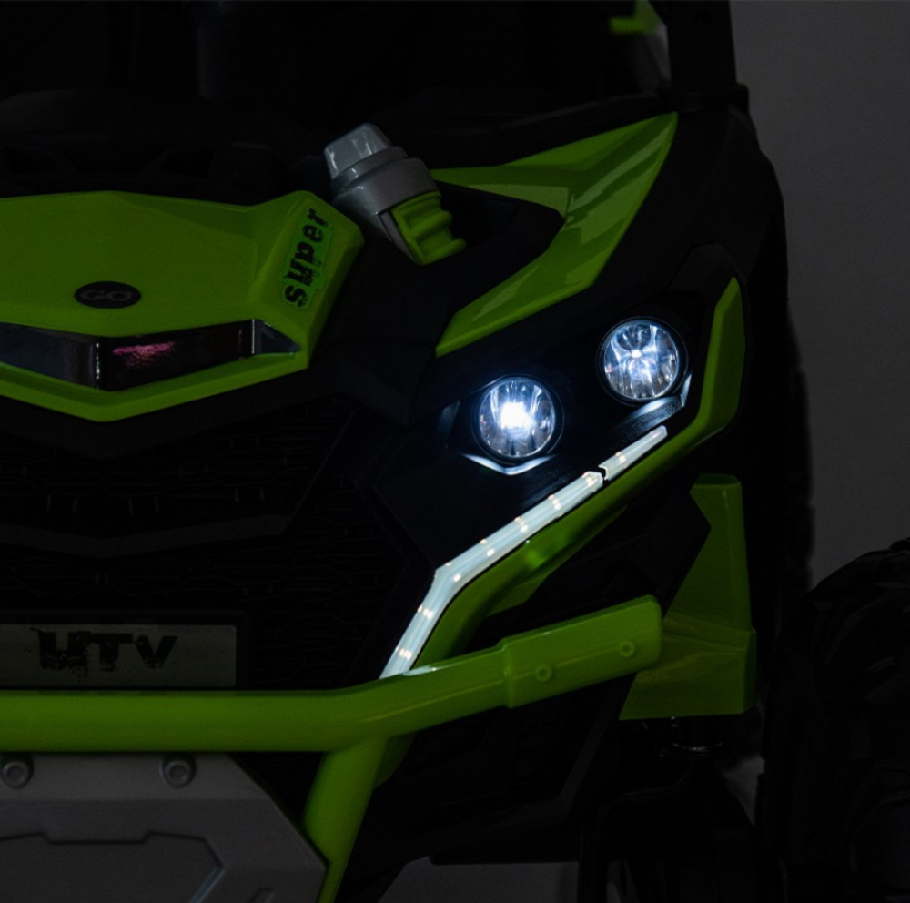 Close-up of a green and black off-road vehicle with illuminated headlights.