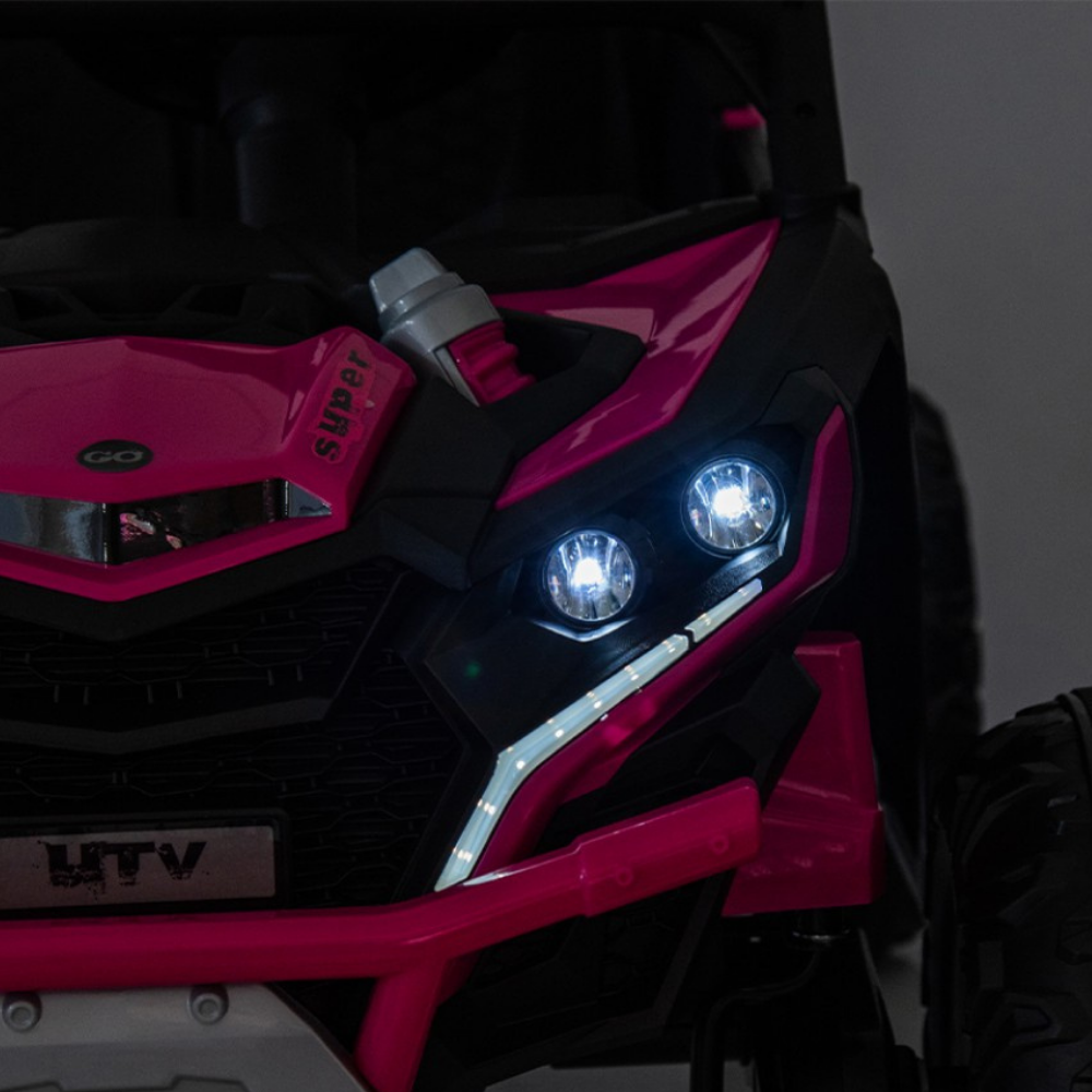 Pink and black off-road vehicle with illuminated headlights on a dark background