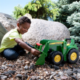 Child playing with a John Deere toy tractor outdoors