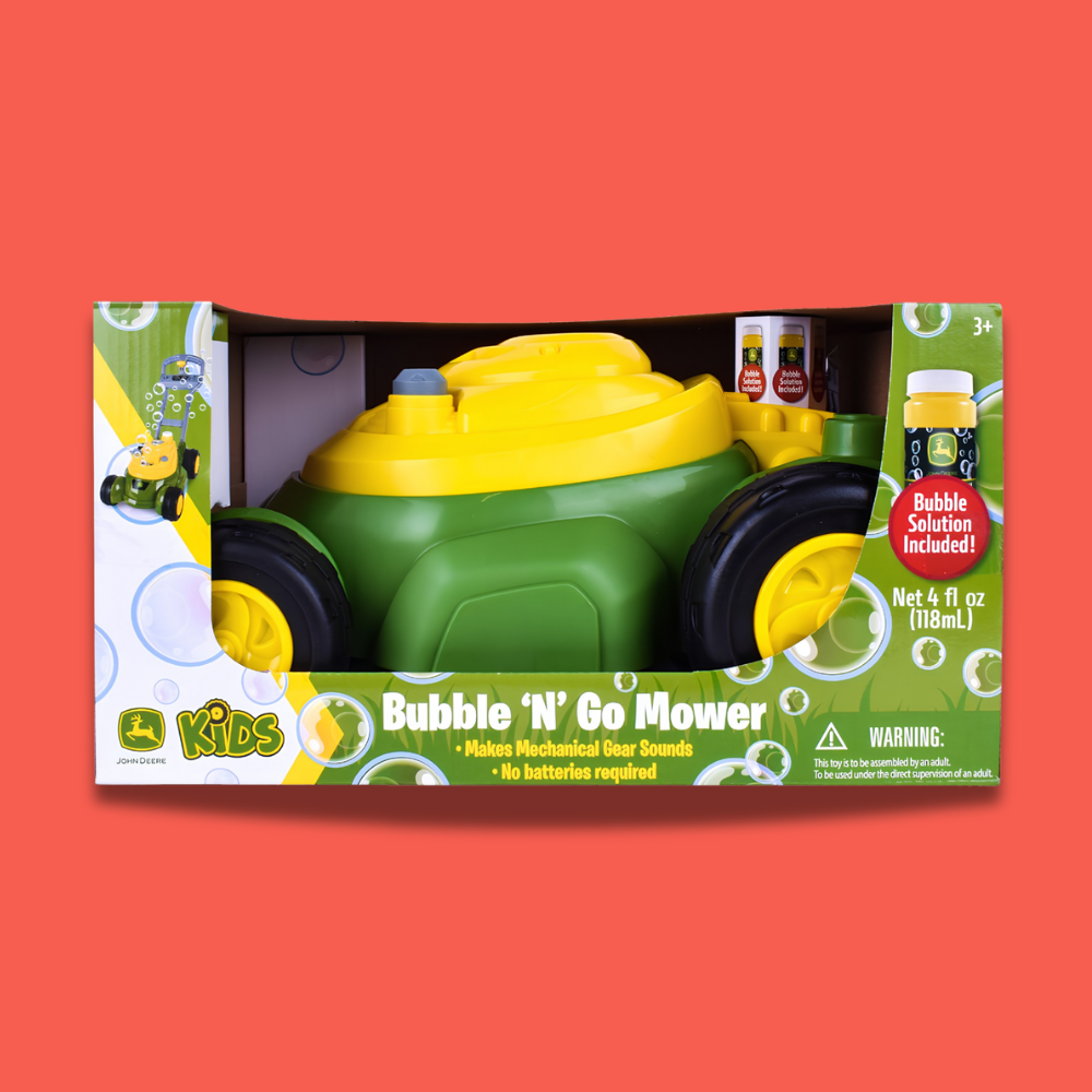John Deere Kids Bubble 'N' Go Mower toy in its retail packaging, featuring a green and yellow plastic mower with black wheels and bubble bottles, set against a solid coral-red background.