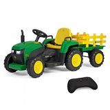 A green and black John Deere-style ride-on toy tractor with a yellow seat and yellow plow attachment, shown on a white background with a black remote control in front.