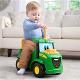 Child playing with a green toy tractor in a living room.