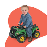 A young child in a blue long-sleeve shirt and jeans sits on the John Deere Buck ATV ride-on toy, gripping the handlebars, against a white background with a red curved design.