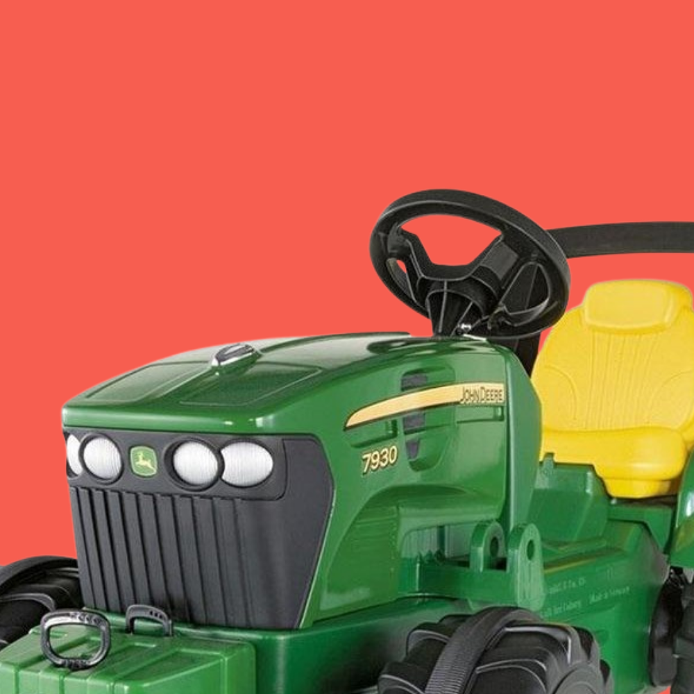 Green toy tractor with black steering wheel and yellow seat on a red background