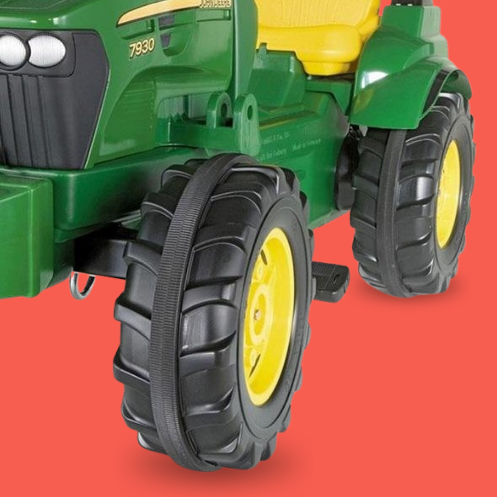 Green toy tractor with large black wheels on a red background
