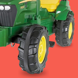 Green toy tractor with large black wheels on a red background