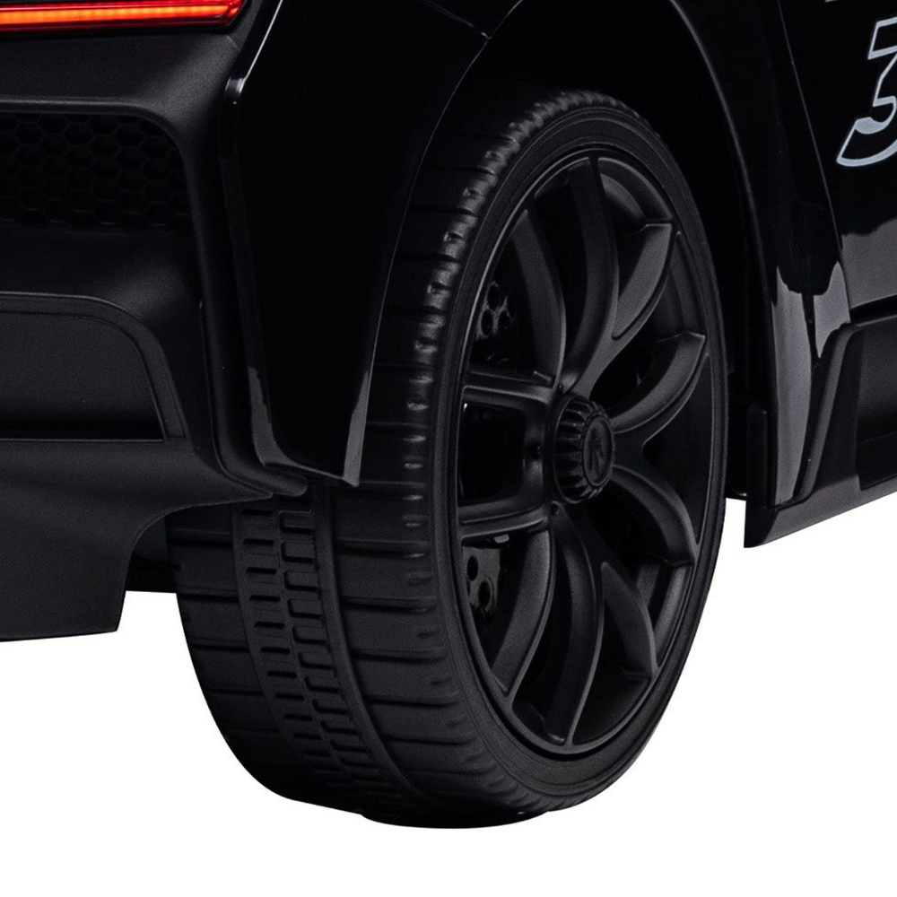 Close-up of a black toy car wheel with a multi-spoke design and black tire, shown against a white background.