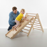Man and child playing on a wooden climbing toy against a white background
