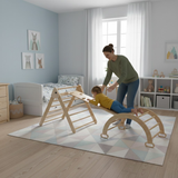 Woman and child playing with wooden climbing toys in a bedroom
