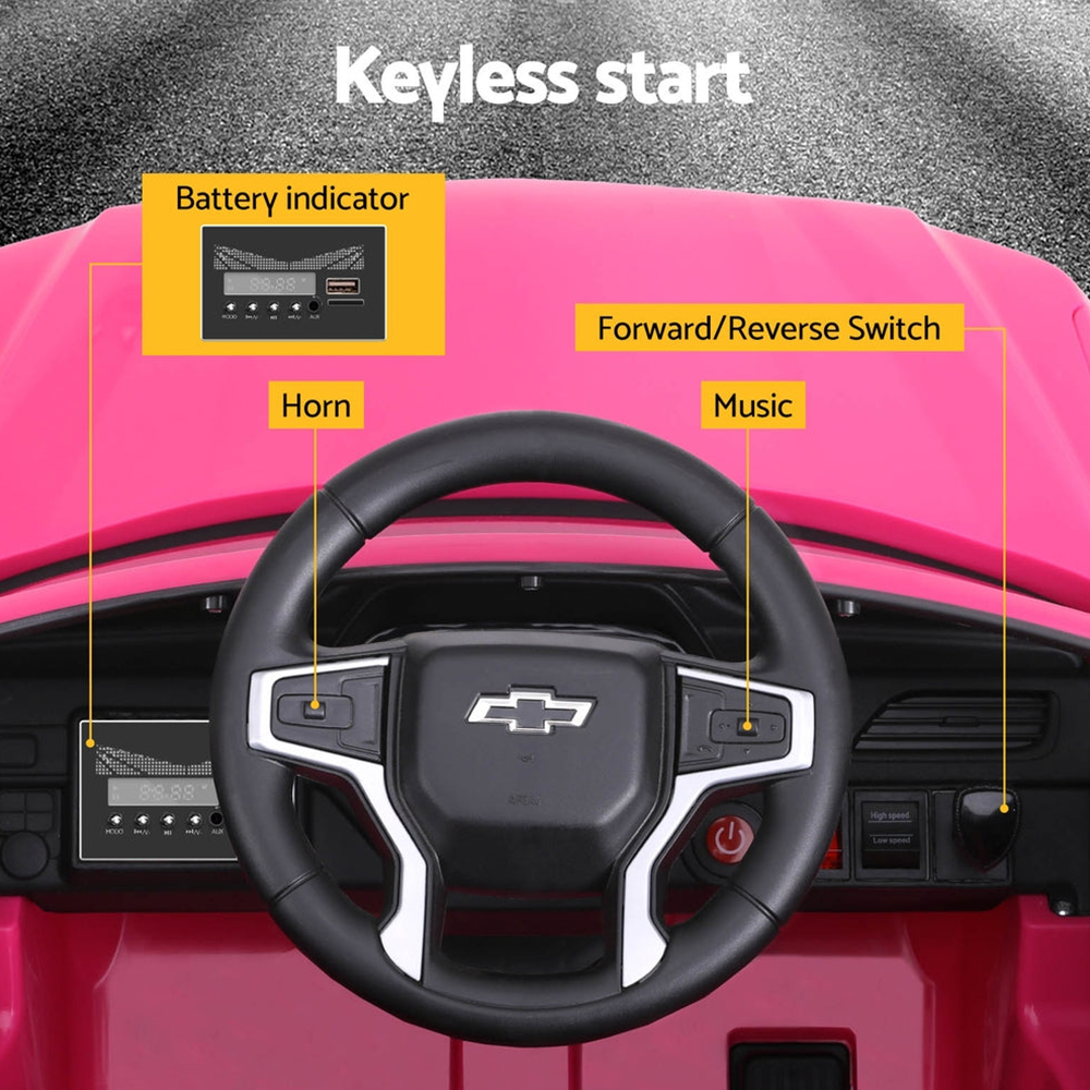 Close-up of the steering wheel and dashboard of the pink ride-on electric car, showing a keyless start button, horn, music, and battery indicator.