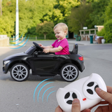 Child playing with a toy car and remote control outdoors.