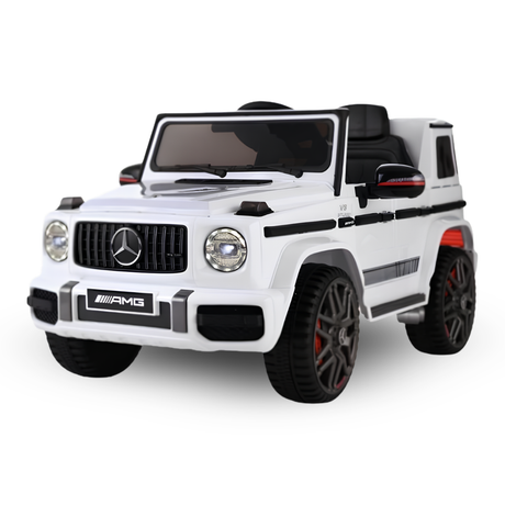 A white Mercedes-Benz AMG kids' ride-on toy car styled like a G-Class SUV, featuring black seats, black wheels, and red accents on the wheel rims, shown against a plain white background.
