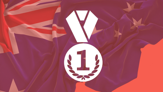 The image shows a design with a medal icon featuring a number "1" within a wreath symbol, representing first place. Behind the icon, there is an Australian flag, with its distinctive Union Jack and stars of the Southern Cross partially visible. The red and blue tones dominate the background, possibly symbolising an achievement or award related to Australia