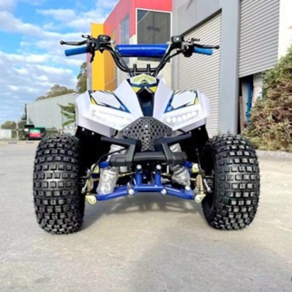 Front view of a blue and white ATV on a paved surface with a building in the background.