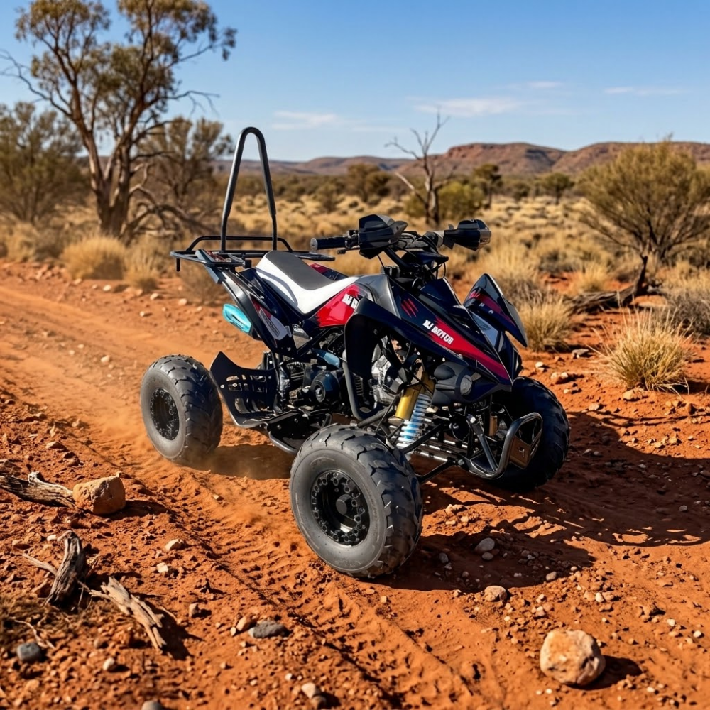 A red, white, and blue mini ATV with a black roll bar is shown driving on a red dirt road in a desert landscape.