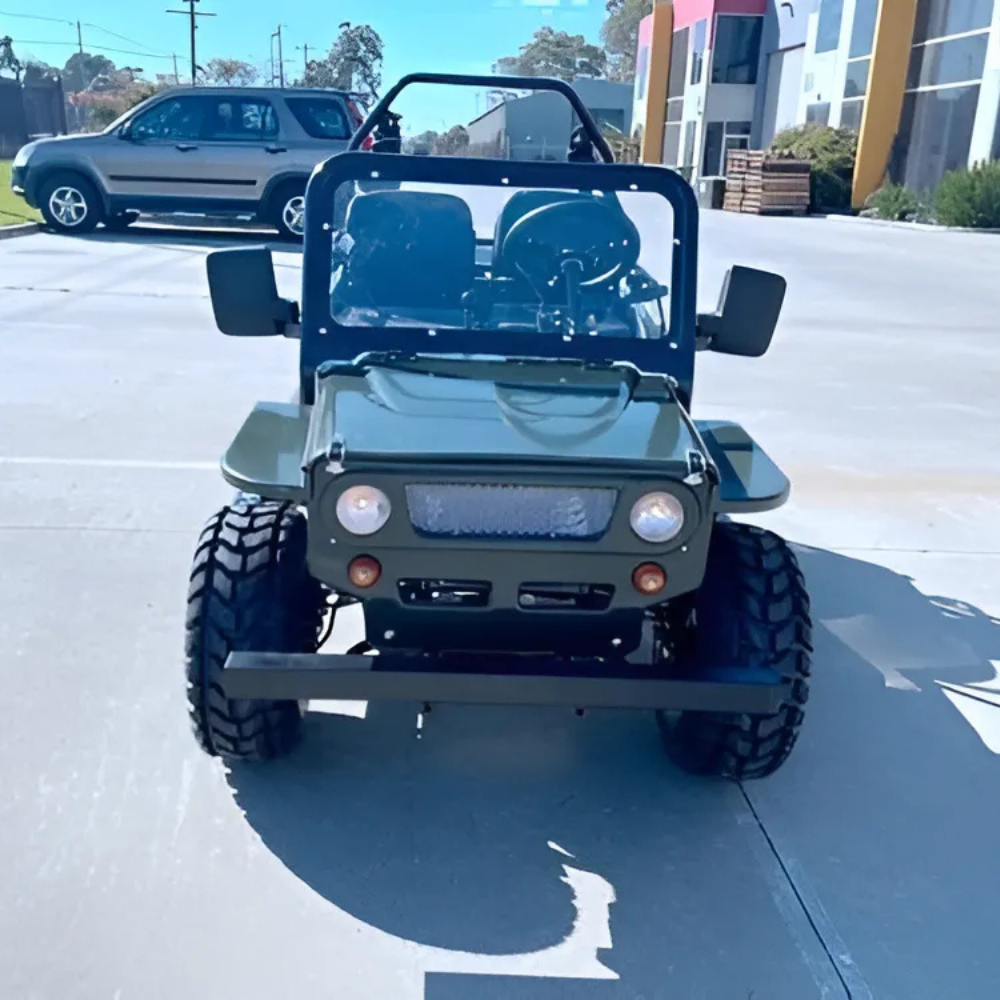 Green off-road vehicle on a paved surface with buildings in the background