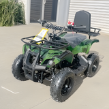 Green and black ATV parked on a concrete surface with a building in the background.
