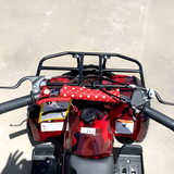 Red ATV with a black rack and red polka dot cover on a concrete surface