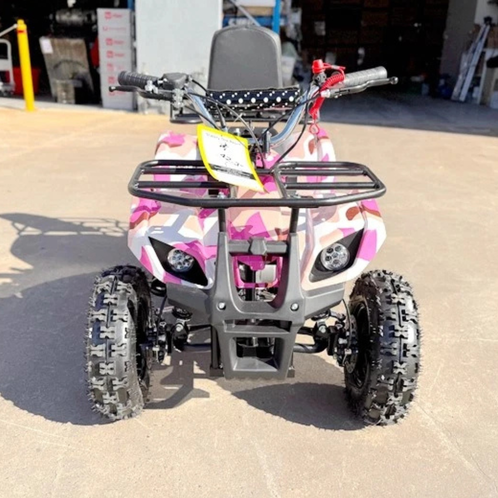 Pink and black camouflage ATV on a concrete surface with a garage in the background