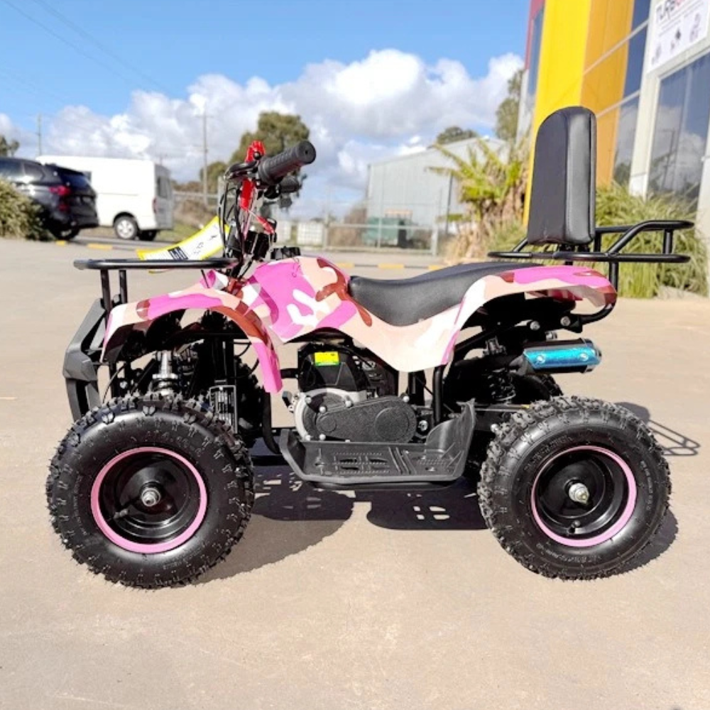 Pink and black quad bike on a paved area with buildings and cars in the background