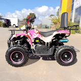 Pink and black quad bike on a paved area with buildings and cars in the background