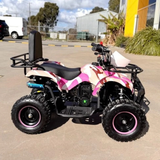 Pink and black ATV parked on a paved area with buildings and vehicles in the background.