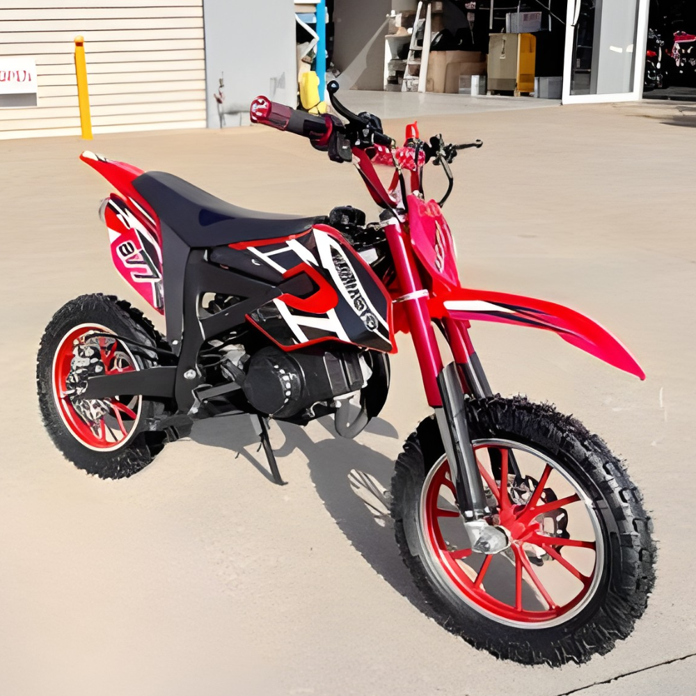 Red and black dirt bike on a concrete surface with a building in the background