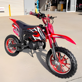 Red and black dirt bike on a concrete surface with a building in the background