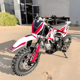 Red and white dirt bike parked on a concrete surface.