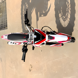 Top-down view of a red and white dirt bike on a sandy surface.