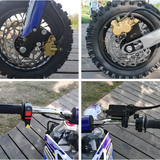 Close-up details of a motorcycle's wheel, suspension, and handlebar on a wooden surface.