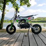 Small dirt bike on a wooden platform with a scenic background of water and trees.