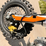 Close-up of a dirt bike wheel and suspension on a concrete surface.