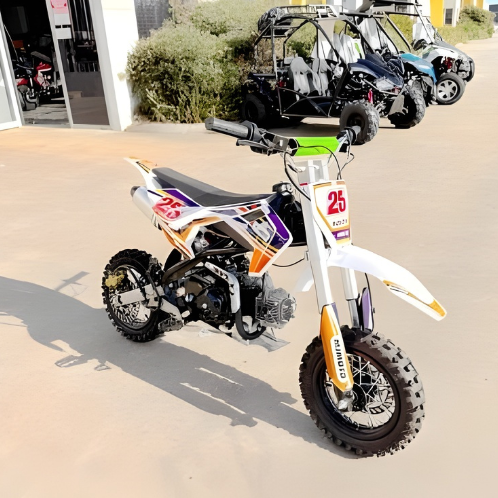Small dirt bike with number 25 on a concrete surface, with off-road vehicles in the background.