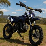 Outdoor shot of blue and black dirt bike on dirt terrain with trees in the background, positioned front-left to show tread and stance.