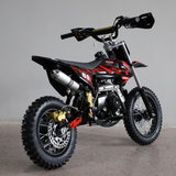 Rear-angled studio shot of the dirt bike, focusing on rear tyre, chain, and exhaust.