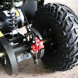 Close-up of a vehicle wheel with suspension and red components on a textured surface.