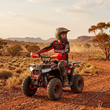 Person riding a red ATV in a desert landscape with mountains in the background